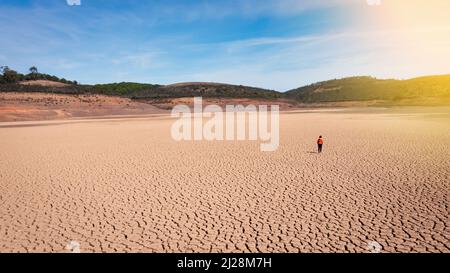 Silhouette eines Mannes auf einem sandigen geknackten leeren, nicht fruchtbaren Land während einer Dürre. Das Konzept der ökologischen Katastrophe auf dem Planeten. Sonniger Tag Stockfoto
