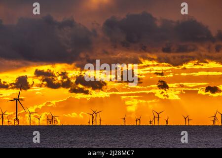 Walney Island, Cumbrian Coast. 30.. März 2022. Wetter in Großbritannien. Nach einem Tag mit Regen, grauem Himmel und einer kalten Nordbrise. Sonnenuntergang von der Cumbrian Coast, Blick über die Irische See zur entfernten Walney Offshore Windfarm. Kredit:greenburn/Alamy Live Nachrichten. Stockfoto