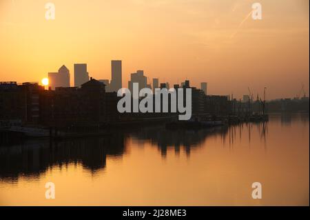 Goldener Sonnenaufgang über der Themse und mit Canary Wharf an der Skyline, London England Stockfoto