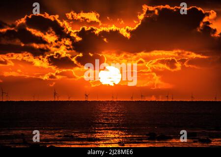 Walney Island, Cumbrian Coast. 30.. März 2022. Wetter in Großbritannien. Nach einem Tag mit Regen, grauem Himmel und einer kalten Nordbrise. Sonnenuntergang von der Cumbrian Coast, Blick über die Irische See zur entfernten Walney Offshore Windfarm. Kredit:greenburn/Alamy Live Nachrichten. Stockfoto