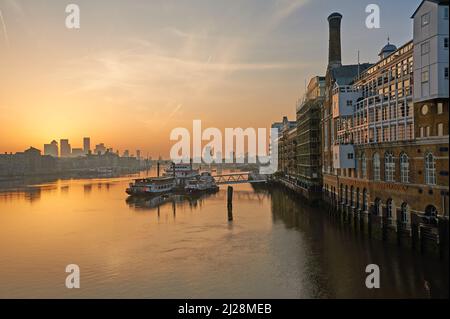 Goldener Sonnenaufgang über der Themse und mit Canary Wharf an der Skyline, London England Stockfoto