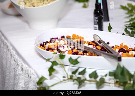 Vegetarisch gerösteter Kürbis, Rote Beete und Feta Salat in einem weißen Server auf einer weißen Tischdecke Stockfoto