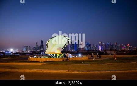 Doha, Katar. 30. März 2022. Kurz nach Sonnenuntergang laufen die Menschen auf der Corniche-Promenade am „Pearl Monument“ vor der Skyline von West Bay Doha. Doha wird am 31. März den FIFA-Kongress und am 1. April die Auslosung der WM 2022 in Katar ausrichten. Quelle: Christian Charisius/dpa/Alamy Live News Stockfoto