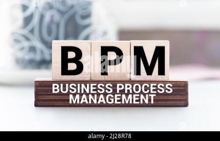 Akronym BPM, Business Process Management. Kleine Holzwürfel mit Buchstaben auf Finanzdokumenten. Stockfoto