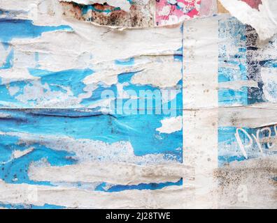 Viele zerrissene, beschädigte Papierplakate, Werbung, abgekratzte Werbung an einer Gebäudewand im Freien, grungige Hintergrundtextur, alte Anzeigen, raues Grunge Stockfoto