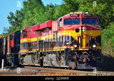 Elgin, Illinois, USA. Zwei Lokomotiven führen durch die Kansas City Southern Railway und einen kanadischen Güterzug durch eine Kreuzung. Stockfoto