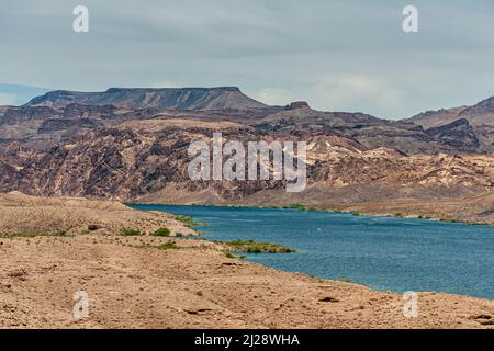 Nelson, Nevada, USA - 21. Mai 2011: Blauer Colorado-Fluss mit den Küsten von Arizona und Nevada unter hellblauer Wolkenlandschaft, trockene Wüste mit felsigen Hügeln o Stockfoto