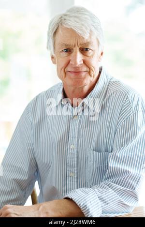 Wir freuen uns auf eine entspannte Zukunft. Porträt eines älteren Mannes, der drinnen sitzt. Stockfoto