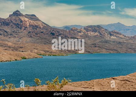 Nelson, Nevada, USA - 21. Mai 2011: Beide trockenen Wüstenstränge des blauen Colorado River unter blauer Wolkenlandschaft. Berge auf der Arizona-Seite und grünes Unkraut Stockfoto