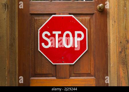 Verkehrsstopschild an der hölzernen Eingangstür. Stockfoto