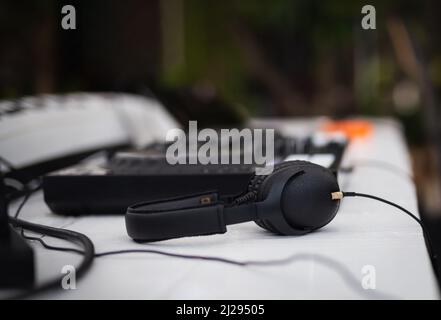Schwarze Kopfhörer und professionelles Mischpult auf dem Tisch. Stockfoto