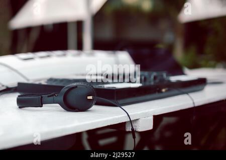 Schwarze Kopfhörer und professionelles Mischpult auf dem Tisch. Stockfoto
