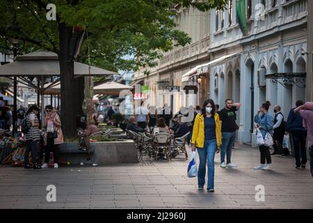 Bild einer weißen Kaukasierin, die in den Straßen von Belgrad, Serbien, läuft, während sie eine schützende Gesichtsmaske trägt, während der 2020 Stockfoto