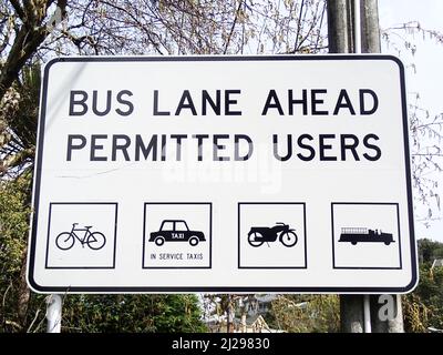 Altmodische Verkehrssymbole zeigen ein Auto, ein Motorrad, einen Fahrrad- und einen Feuerwehrmotor auf der Straßenbeschilderung. Diese sind in Ordnung, eine Stadtbusspur in Neuseeland zu benutzen. Stockfoto