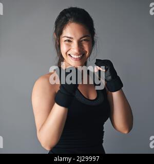 Shes hat viel Kampf in sich. Studioaufnahme einer weiblichen Kickboxerin vor grauem Hintergrund. Stockfoto