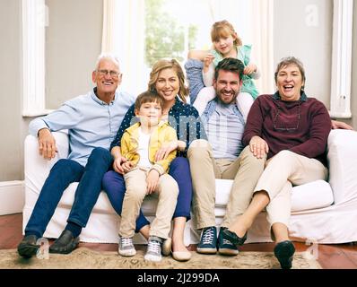 Es gibt keine Liebe wie die Liebe einer Familie. Aufnahme einer Familie mit mehreren Generationen, die zu Hause auf dem Sofa sitzt. Stockfoto