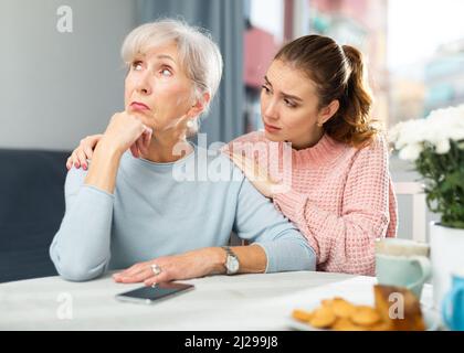 Erwachsene Tochter beruhigend verärgert Mutter nach Streit am Tisch Stockfoto