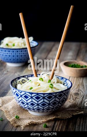 Vorderansicht einer Schüssel mit Nudeln mit eingesteckten Essstäbchen. Stockfoto