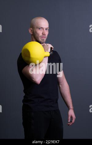 Typ mit gelber Kettlebell-Turnhalle anonymer gelber Rüde, nachmittags sportlicher Lifestyle für das Training vom Gummigewichtlifting, Südost-filipino Stockfoto