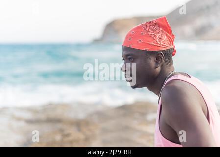 Schwarzer Mann, der das Meer betrachtet und das gute Wetter genießt Stockfoto