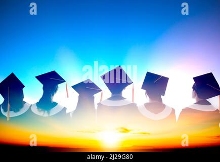 Doppelbelichtung der Silhouette Graduation Group, die den Sonnenaufgang feiert und beobachtet Stockfoto