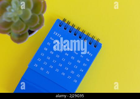 Blauer Desktop-Kalender für Mai 2022 für die Planung auf gelbem Hintergrund Stockfoto