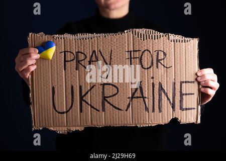Frau hält ein Banner mit Anti-Kriegs-Botschaft. Protest gegen die russische Intervention in der Ukraine, Aktivismus und Menschenrechtsbewegung. Konzept der Standi Stockfoto