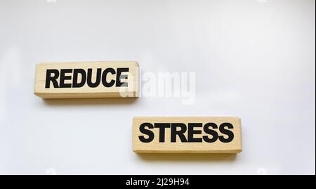 Holzblöcke mit der Aufschrift STRESSREDUKTION auf weißem Hintergrund. Blick von oben. Flach liegend. Marketingkonzept. Stockfoto