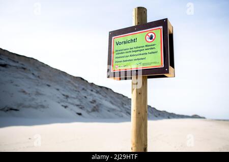 Norderney, Deutschland. 12. März 2022. Ein Schild mit der Aufschrift „Achtung!“ Steht vor der Abbruchkante am Nordstrand der Insel. Nach den schweren Winterstürmen mit Sturmfluten und erheblichen Sandverlusten will das Land Niedersachsen den betroffenen ostfriesischen Inseln finanziell helfen. Quelle: Hauke-Christian Dittrich/dpa/Alamy Live News Stockfoto