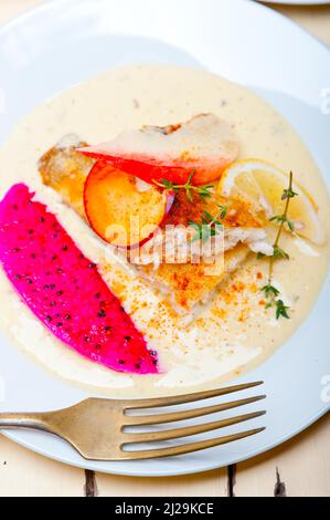 Brassen-Orangen-Filetbutter, gebraten mit frischer Pfirsichpflaume und Dragonfruit-Scheiben Thymian darauf Stockfoto