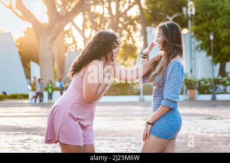 Zwei glückliche Mädchen, die auf der Straße lachen, zwei Frauen, die auf der Straße reden und lachen, zwei Frauen, die Spaß haben Stockfoto