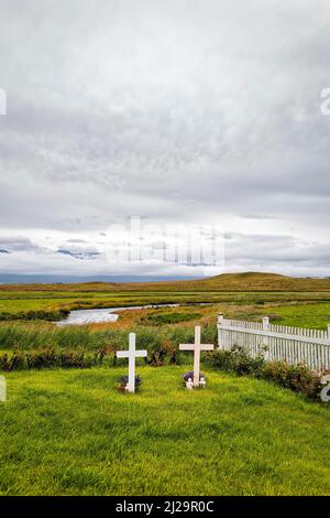 Friedhof, zwei Gräber nebeneinander, weiße Holzkreuze auf einer Wiese mit Zaun, Fluss am Horizont, Textfreiraum, Nordwest-Island Stockfoto