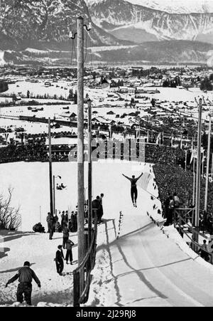 Blick auf verschneite Garmisch-Partenkirchen und die sechzigtausend Zuschauer im Skistadion beim Springen von der kleinen Schanze in der Stockfoto