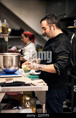 Okay, lasst uns zur Arbeit gehen. Aufnahme eines fokussierten Küchenchefs, der in der Küche eines Restaurants ein Gericht zubereitet. Stockfoto