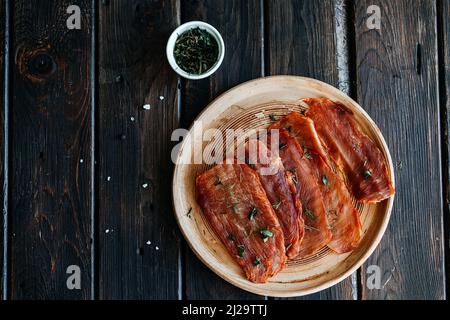 Getrocknetes Huhn, getrocknetes Geflügel, in Streifen geschnitten auf einem Teller auf einem hölzernen Hintergrund. Hochwertige Fotos Stockfoto
