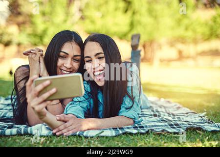 Ich muss im Sommer Selfies machen. Ausgeschnittene Aufnahme von zwei jungen Freunden, die zusammen ein Selfie im Park machen. Stockfoto