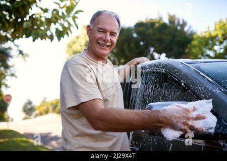 Sich um sein Auto kümmern. Porträt eines Mannes, der draußen ein Auto wäscht. Stockfoto