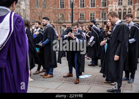 Absolventen des Imperial College London genießen die Atmosphäre außerhalb der Royal Albert Hall, obwohl Eltern oder Familienmitglieder nicht teilnehmen durften. Stockfoto