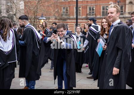 Absolventen des Imperial College London genießen die Atmosphäre außerhalb der Royal Albert Hall, obwohl Eltern oder Familienmitglieder nicht teilnehmen durften. Stockfoto