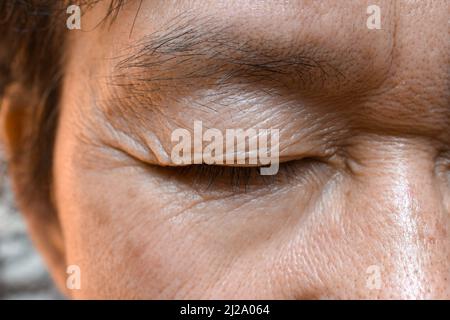 Falten um das geschlossene Auge des älteren asiatischen Mannes. Nahaufnahme. Stockfoto