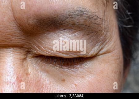 Falten um das geschlossene Auge des älteren asiatischen Mannes. Nahaufnahme. Stockfoto