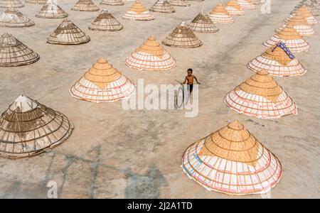 Brahmanbaria, Chittagong, Bangladesch. 31. März 2022. Kinder laufen und spielen zwischen Hunderten traditioneller Reismühlen aus Bambus.nach dem Kochen wird das Getreide von Arbeitern in Haufen gefegt und bis zu acht Stunden lang in Brahmanbaria, Bangladesch, getrocknet. Die Reismühlenarbeiter begannen ihre Arbeit von sehr früh morgens von 5 bis 2pm Uhr täglich. Nach der Mittagspause spielen die Kinder der Arbeiter ihre Nachmittagsspiele mit Freunden in diesem Reismühlenfeld. (Bild: © Mustasinur Rahman Alvi/ZUMA Press Wire) Bild: ZUMA Press, Inc./Alamy Live News Stockfoto