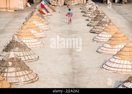 Brahmanbaria, Chittagong, Bangladesch. 31. März 2022. Kinder laufen und spielen zwischen Hunderten traditioneller Reismühlen aus Bambus.nach dem Kochen wird das Getreide von Arbeitern in Haufen gefegt und bis zu acht Stunden lang in Brahmanbaria, Bangladesch, getrocknet. Die Reismühlenarbeiter begannen ihre Arbeit von sehr früh morgens von 5 bis 2pm Uhr täglich. Nach der Mittagspause spielen die Kinder der Arbeiter ihre Nachmittagsspiele mit Freunden in diesem Reismühlenfeld. (Bild: © Mustasinur Rahman Alvi/ZUMA Press Wire) Bild: ZUMA Press, Inc./Alamy Live News Stockfoto