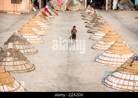 Brahmanbaria, Chittagong, Bangladesch. 31. März 2022. Kinder laufen und spielen zwischen Hunderten traditioneller Reismühlen aus Bambus.nach dem Kochen wird das Getreide von Arbeitern in Haufen gefegt und bis zu acht Stunden lang in Brahmanbaria, Bangladesch, getrocknet. Die Reismühlenarbeiter begannen ihre Arbeit von sehr früh morgens von 5 bis 2pm Uhr täglich. Nach der Mittagspause spielen die Kinder der Arbeiter ihre Nachmittagsspiele mit Freunden in diesem Reismühlenfeld. (Bild: © Mustasinur Rahman Alvi/ZUMA Press Wire) Bild: ZUMA Press, Inc./Alamy Live News Stockfoto