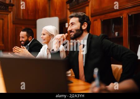 Glückliche Geschäftsleute und Geschäftsmänner, die in der Konferenzsitzung im Sitzungssaal sitzen Stockfoto