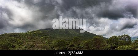 Arenal Vulkan in den Wolken im Hintergrund eingebettet. Provinz La Fortuna, Costa Rica.Vulkanlandschaft. Stockfoto