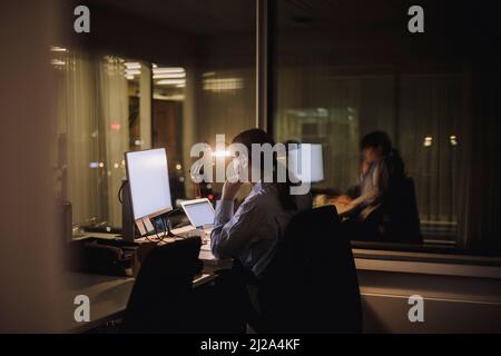 Junge Geschäftsfrau, die spät am Arbeitsplatz am Computer arbeitet Stockfoto