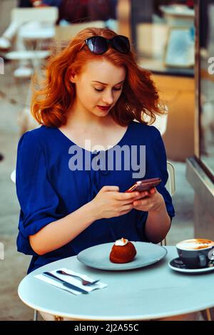 Junge Frau im Coffee Shop fotografieren Dessert Cupcake Influencer Stockfoto