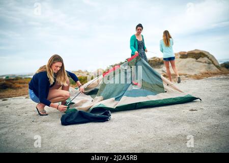 Das Campen mit Ihren Beties ist das, was das Leben bedeutet. Aufnahme einer Gruppe von Freundinnen, die im Freien ein Zelt aufschlagen. Stockfoto