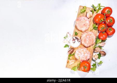 Burger-Koteletts aus Huhn, putenfleisch. Rohes Hackfleisch aus Hackfleisch auf einem Schneidebrett mit Gewürzen, Kräutern zum Kochen Stockfoto